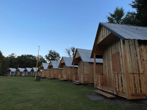 a row of wooden houses sitting in a field at Areál Kamínka - CHATKA PREMIUM in Roštín