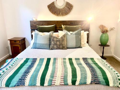 a bedroom with a large bed with a green vase at Ombak Beach Villa ~ Margaret River in Gnarabup