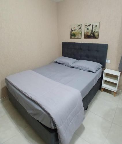 a bedroom with a large bed and a white chair at Aconchego e sossego in São Paulo