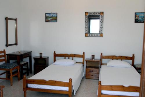 a bedroom with two beds and a chair and a mirror at Stegnailion in Archangelos