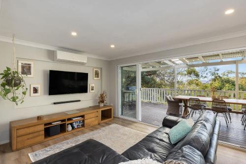 a living room with a couch and a flat screen tv at Cottage on Riv - Winter Holiday Mid-Week Special in Terrigal
