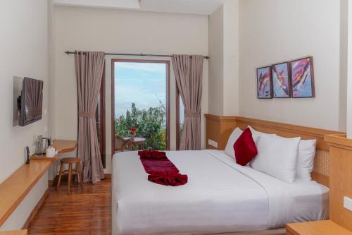 a bedroom with a large white bed with a window at Munduk Tentrem Resort in Munduk