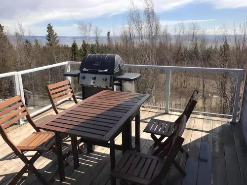 a grill on a deck with two chairs and a table at Bleuzen appartement du haut in Petite-Rivière-Saint-François