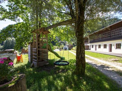 a playground with a slide next to a tree at Cowshed with private sauna in Unken