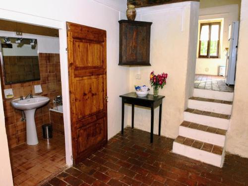 ein Badezimmer mit Waschbecken und Holztür in der Unterkunft Rustic apartment with swimming pool in Modigliana