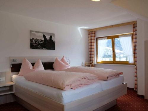a bedroom with a large bed with pink pillows at 1-bedroom apartment in Riezlern