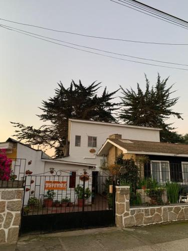 a white house with a fence in front of it at Hostal Saint Michell. El Quisco in El Quisco