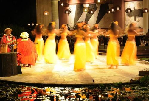 a group of women in yellow dresses dancing on a stage at Tahiti Lagoon Resort in Punaauia