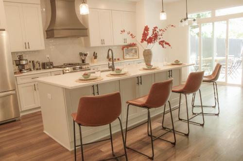 a kitchen with white cabinets and a island with bar stools at Hot Tub Pool Table Fire Pit 5min to Uptown in Charlotte