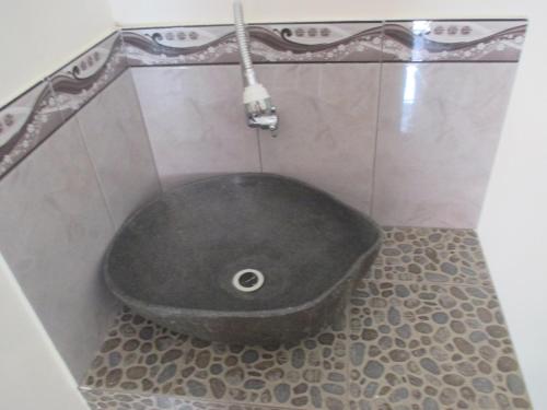a black bath tub sitting in a bathroom at Rumah Ukhi Guest House in Yogyakarta
