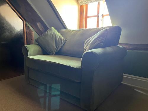 a blue chair sitting in a room with a window at Rooftops Loft in Hay-on-Wye