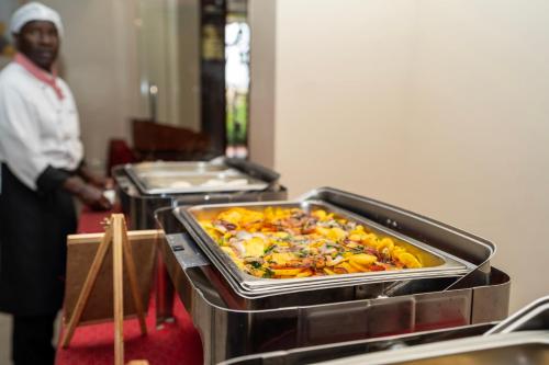 a man standing in a kitchen with a tray of food at Esiankiki Resort & Spa - Nanyuki in Nanyuki