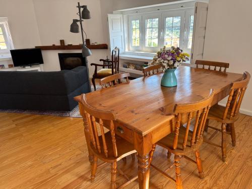 a wooden table with chairs and a vase of flowers at Casa do Mestre João in São Martinho