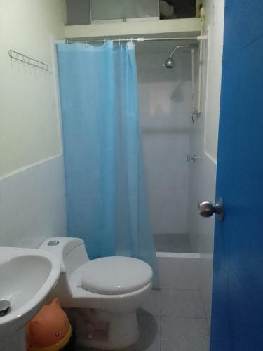 a bathroom with a toilet and a blue shower curtain at Hospedaje TUTUMEME in Churín