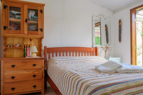 a bedroom with a bed with a wooden dresser and a drawer at Conforto no Centro de Pirenópolis in Pirenópolis