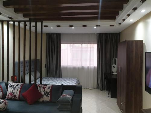 a bedroom with a bed and a couch and a television at Superb studio at the ocean in Rabat