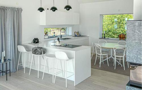 オーケシュバーリアにあるBeach Front Home In Åkersberga With Saunaの白いキャビネットとテーブルと椅子のあるキッチン