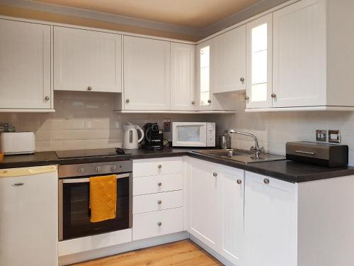 a white kitchen with white cabinets and a microwave at Leven Lodge 1 - Uk46042 in Balloch