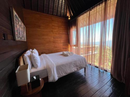 a bedroom with a bed and a large window at Harvest Palace Munduk in Munduk