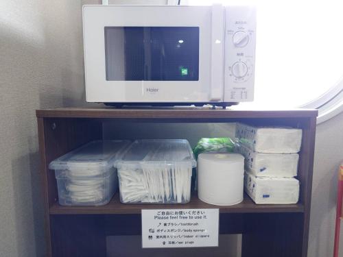 a microwave sitting on top of a shelf with containers at N's Hotel 平和公園 in Hiroshima