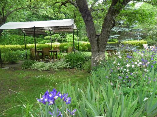 a garden with a gazebo and purple flowers at Gîte cosy en bord de rivière avec jardin, proche village médiéval, idéal famille, animaux acceptés - FR-1-489-247 in Hérisson