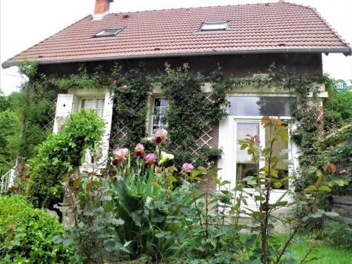 a house with a bunch of flowers in front of it at Gîte cosy en bord de rivière avec jardin, proche village médiéval, idéal famille, animaux acceptés - FR-1-489-247 in Hérisson