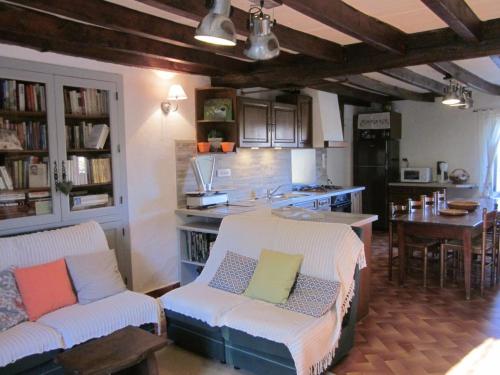 une cuisine avec deux canapés blancs et une table ainsi qu'une cuisine avec un comptoir dans l'établissement Maison familiale avec jardin clos, cheminée, animaux acceptés et internet à Ferrières-sur-Sichon - FR-1-489-552, à Ferrières-sur-Sichon