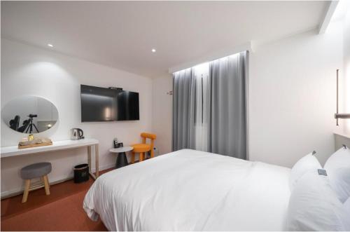 a bedroom with a white bed and a table and a mirror at No 25 Hotel Namgumi Branch in Chilgok