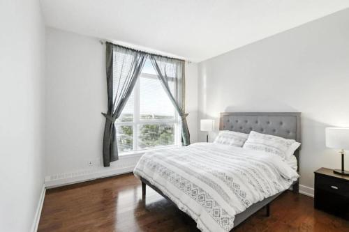 a white bedroom with a bed and a window at 17th Avenue Paranomas Escape in Calgary