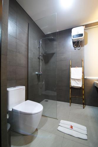 a bathroom with a toilet and a glass shower at Casa de Lily in Tabanan
