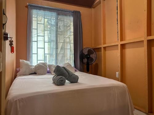 a bed with two stuffed animals on it with a window at Tortuguero Family House in Colorado