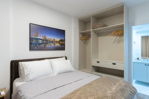 a bedroom with a bed and a tv on the wall at CONFORTO JH PALHANO, Ap 1507 in Londrina