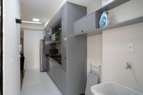 a white bathroom with a sink and a refrigerator at CONFORTO JH PALHANO, Ap 1507 in Londrina