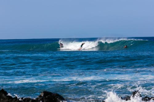 two people riding a wave in the ocean at Hale Waima Lani in Puako