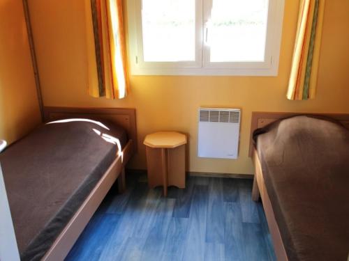 a small room with two beds and a window at Charmant Chalet Familial avec Terrasse et Activités d'Été - Camping 2 Étoiles - FR-1-489-400 in Treignat