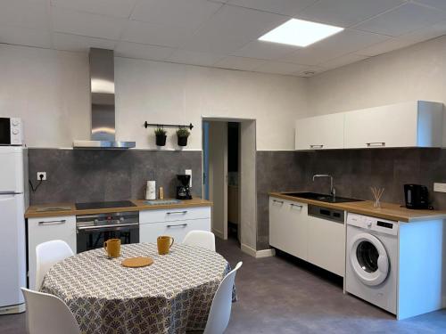 une cuisine avec une table et une machine à laver dans l'établissement Maison rénovée au calme avec jardin, terrasse et garage, à 10 min de Moulins, draps et serviettes inclus - FR-1-489-372, à Villeneuve-sur-Allier