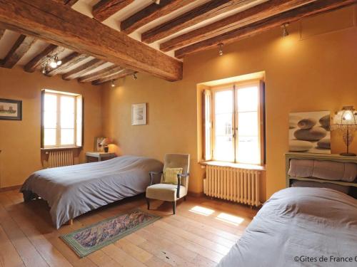 a bedroom with two beds and a chair and two windows at Maison de charme avec piscine intérieure, grand jardin, et paysages magnifiques en pleine campagne - FR-1-497-164 in Rémalard en Perche