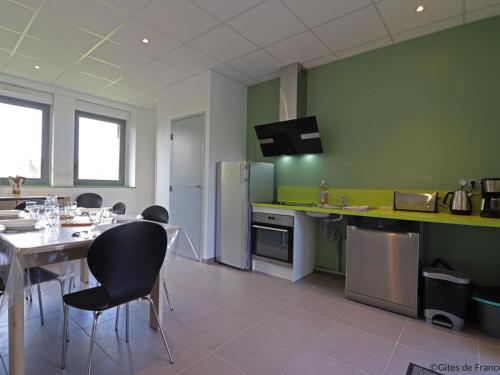 - une cuisine avec une table, des chaises et des murs verts dans l'établissement Gîte adapté aux handicapés, idéal randonneurs et familles - FR-1-497-234, à Lonlay-lʼAbbaye