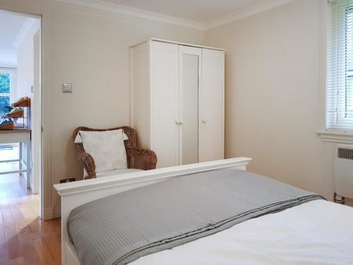 a bedroom with a bed with a chair and a cabinet at Leven Lodge 3 - Uk46045 in Balloch