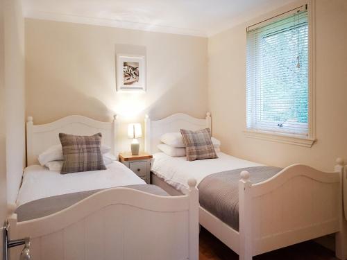 two white beds in a room with a window at Leven Lodge 3 - Uk46045 in Balloch