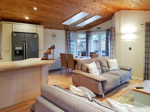 a kitchen and living room with a couch and a table at Kingfisher Lodge - Uk46046 in Balloch