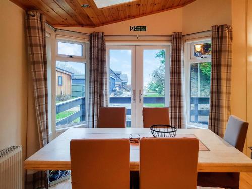 a dining room table with chairs and a large window at Kingfisher Lodge - Uk46046 in Balloch
