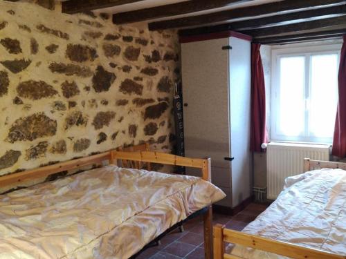 a bedroom with a bed and a stone wall at Gîte indépendant à Saint-Genest avec jardin clos - FR-1-489-562 in Saint-Genest