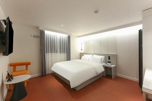a bedroom with a white bed and a table and a chair at No 25 Hotel Namgumi Branch in Chilgok
