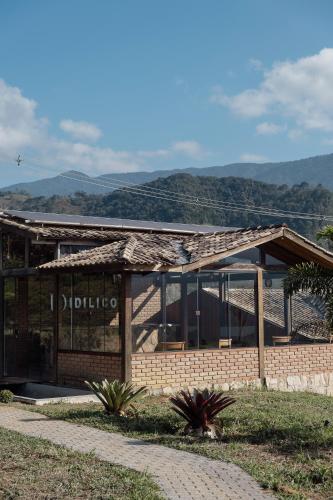 a building with a roof with mountains in the background at Idilicos Mauá in Visconde De Maua