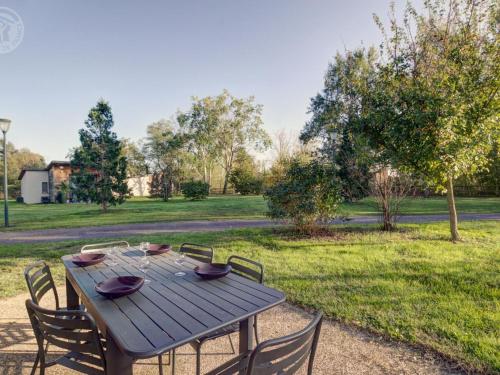 a wooden picnic table with chairs and a field at Chalets bord d'étang avec terrasse privée et équipements loisir, parfaits pour une escapade nature - FR-1-496-79 in Veauchette