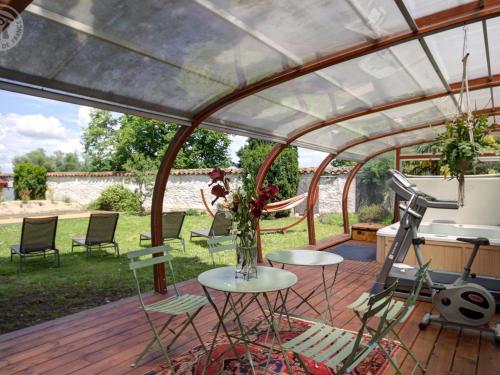 a pergola with a table and chairs on a deck at Gîte de charme avec spa, sauna et jardin privatif à Montbrison - FR-1-496-309 in Montbrison