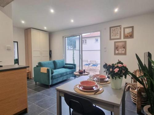 un salon avec une table et un canapé bleu dans l'établissement Gîte cosy pour 2 à Montrond-les-Bains avec parking privatif - FR-1-496-342, à Montrond-les-Bains