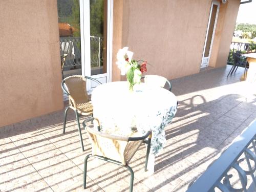 a white table with a vase of flowers on a patio at Apartments Jerković in Stari Grad