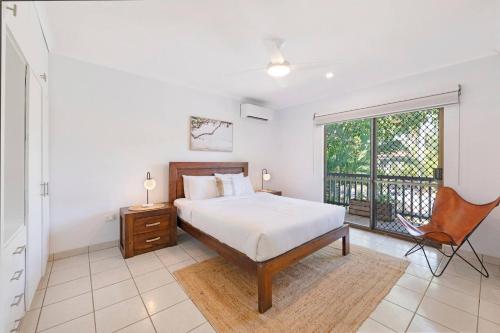 una camera da letto con un letto, una finestra e una sedia di Casuarina Cove - Foreshore Tropical Escape near CBD a Nightcliff